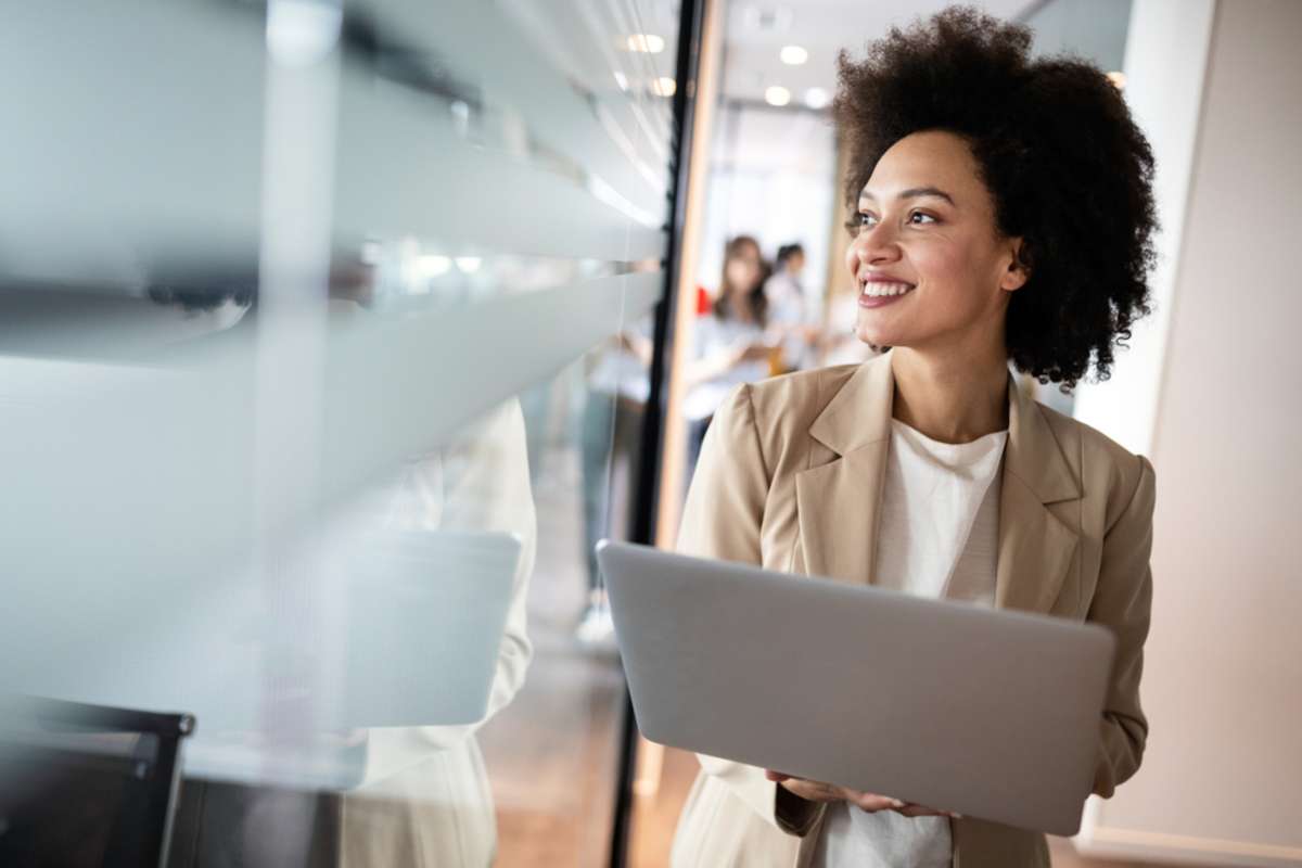 Portrait of an attractive young african businesswoman smiling while standing by windows in office